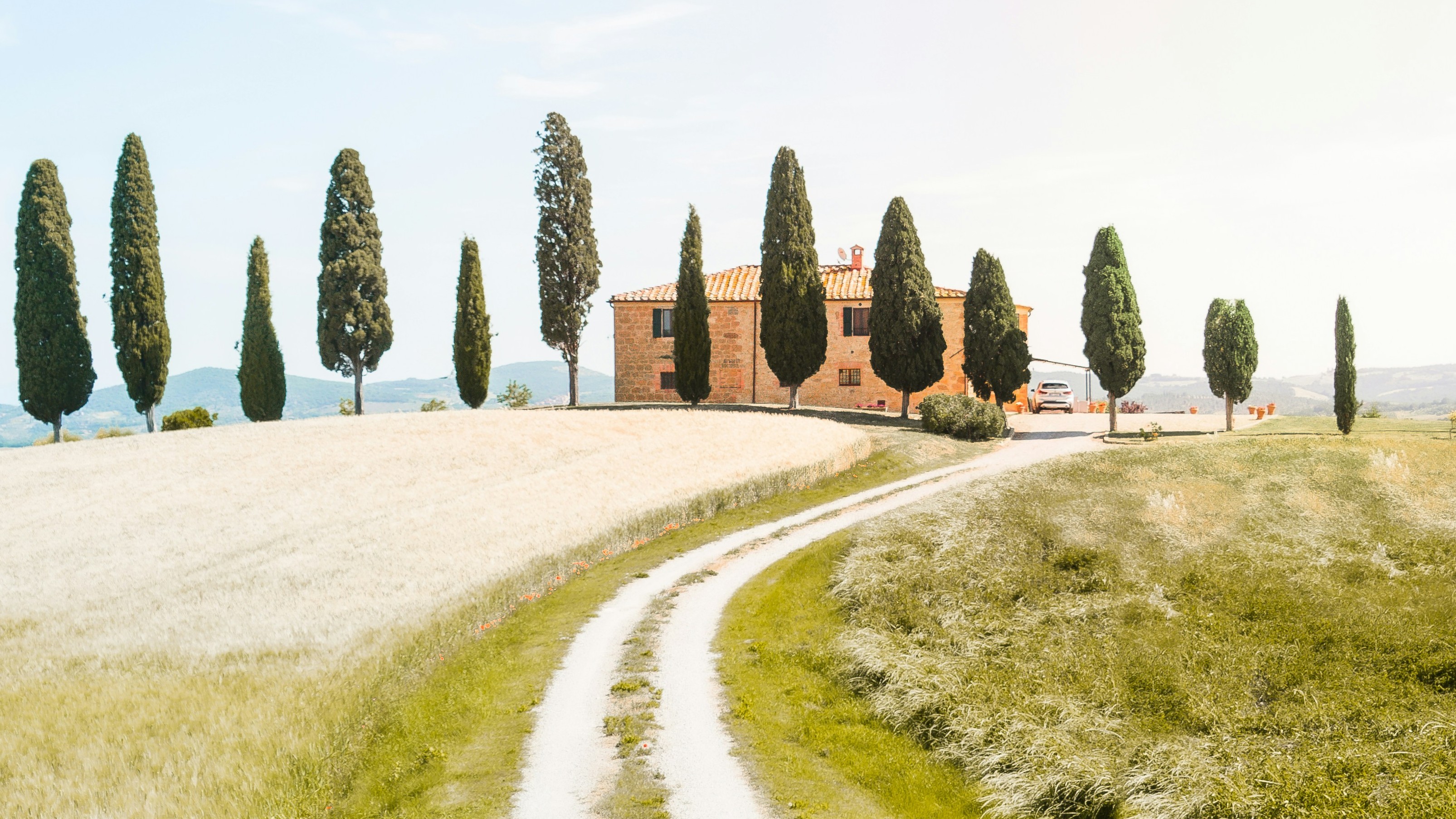 A Tuscany, Italy landscape with a home that has terracotta tile roof.