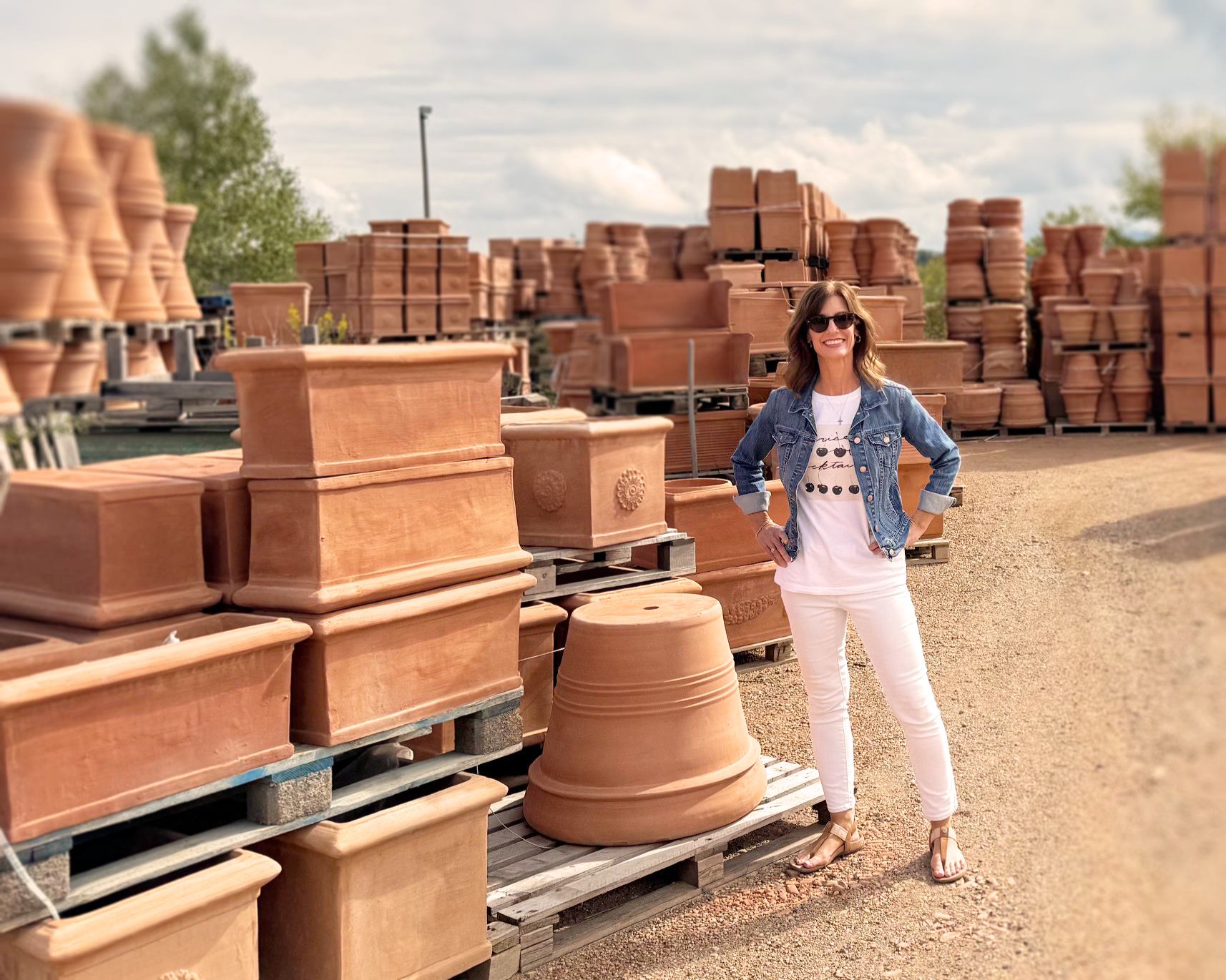 Lorin Catalena standing with terracotta pots stacked all around her in Italy